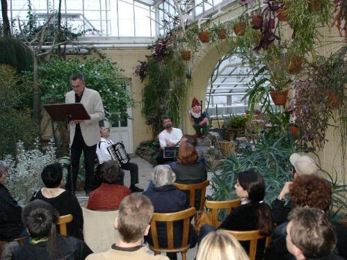Buchautor Manfred Fock liest im hellen Sakko an einem Notenständer beim Krimifestival im Gewächshaus.