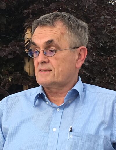 Buchautor Manfred Fock im hellblauen Hemd mit Brille blickt im Profil aufmerksam nach links.