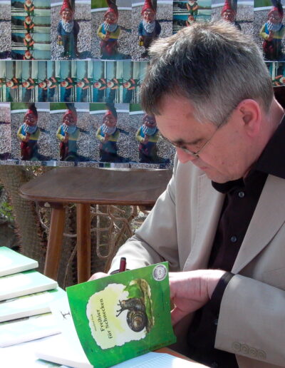 Buchautor Manfred Fock signiert sein Buch Freibier für Schnecken an einem Büchertisch.