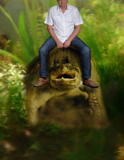 Buchautor Manfred Fock in einer humorvollen Fotomontage sitzend auf einer riesigen Schnappschildkröte.